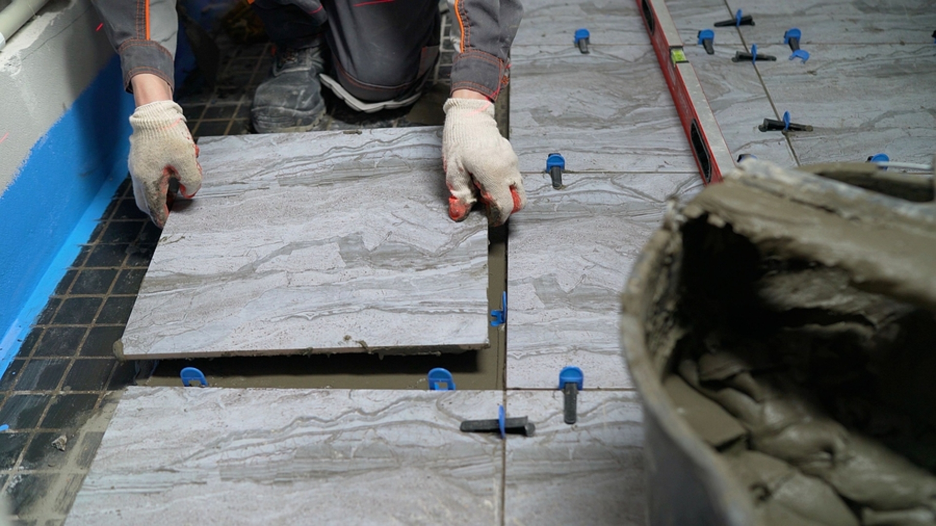 The process of laying ceramic tiles on glue-smeared floors. Workers hands with tiles close up. Applying tile adhesive to the floor. The process of laying tiles on the floor.